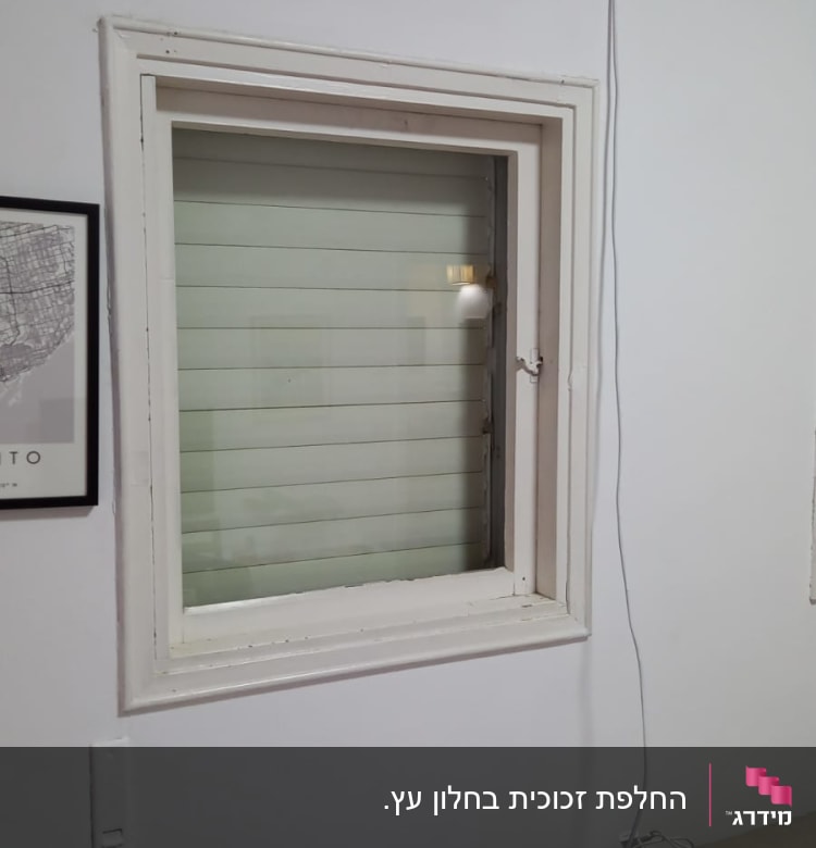 חלון זכוכית עם תריסים סגורים בתוך מסגרת לבנה